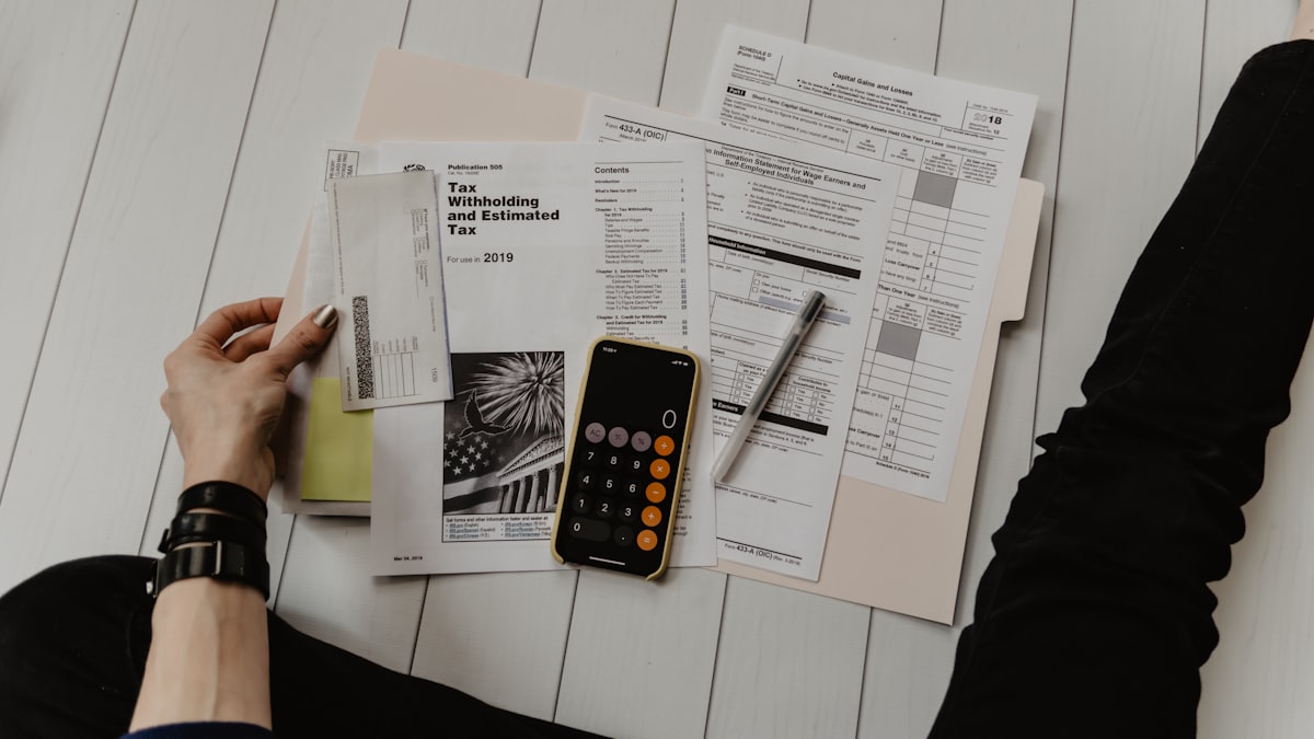 Calculator and tax papers on a wooden desk next to a passport