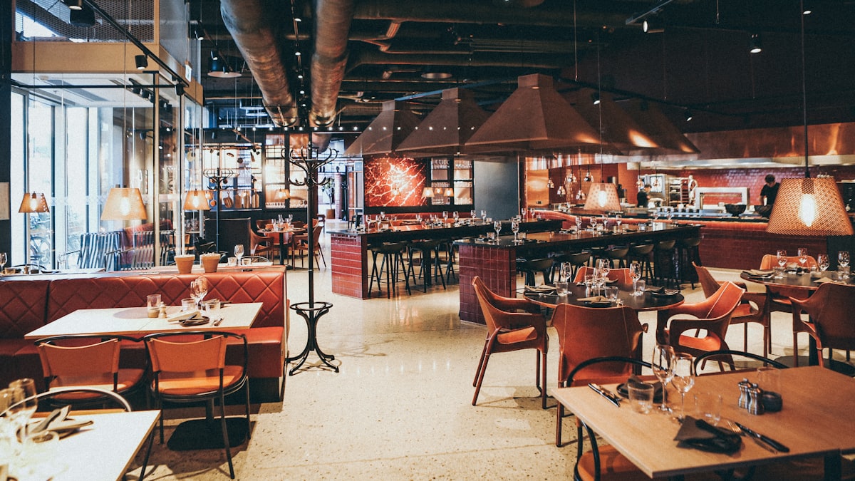 Young worker stacking chairs in an empty restaurant after closing time